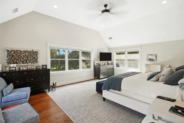 a spacious bedroom with a bed and wooden floor