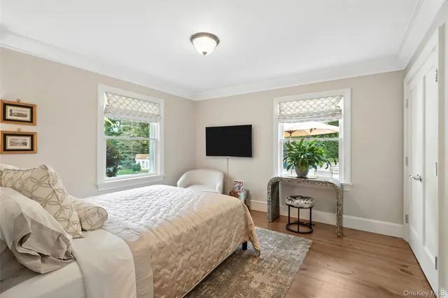 a bedroom with a bed a chair and a flat screen tv