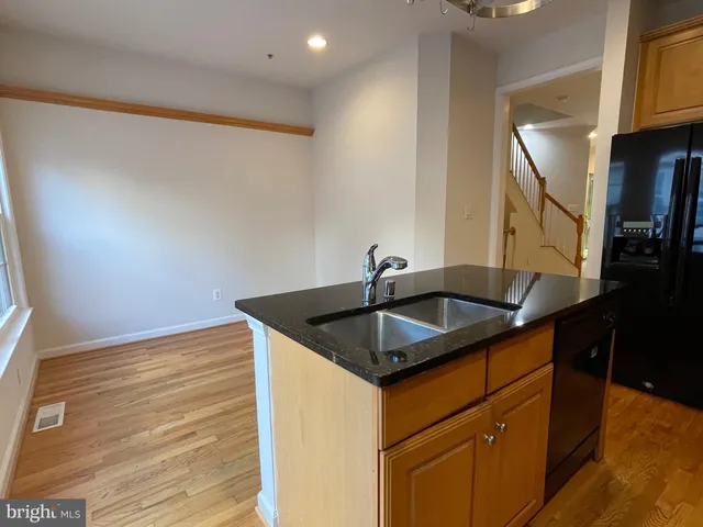 a kitchen with granite countertop wooden floors stainless steel appliances a window and a counter space