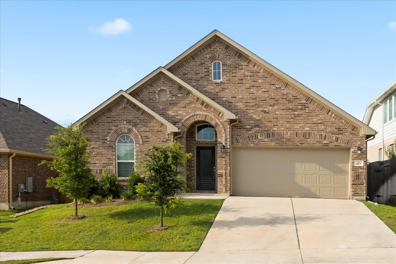 423 Leadtree Loop Buda, TX 78610 - Photo 1 of 1 View of front of home with brick siding, concrete driveway, a front lawn, and an attached garage