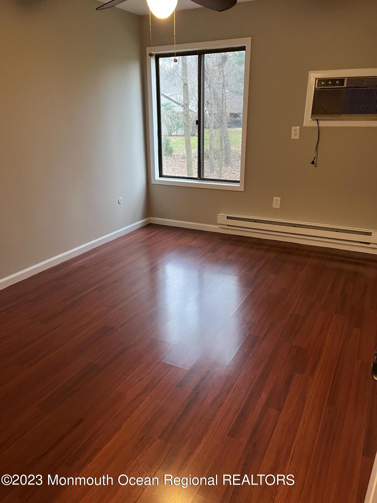 136 Amberly Drive, Unit F Manalapan, NJ 07726 - Photo 5 of 14 an empty room with wooden floor and windows