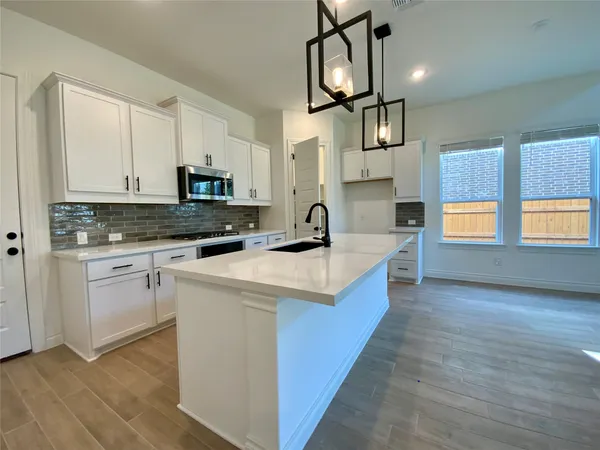 a kitchen with stainless steel appliances granite countertop a stove a sink and a microwave