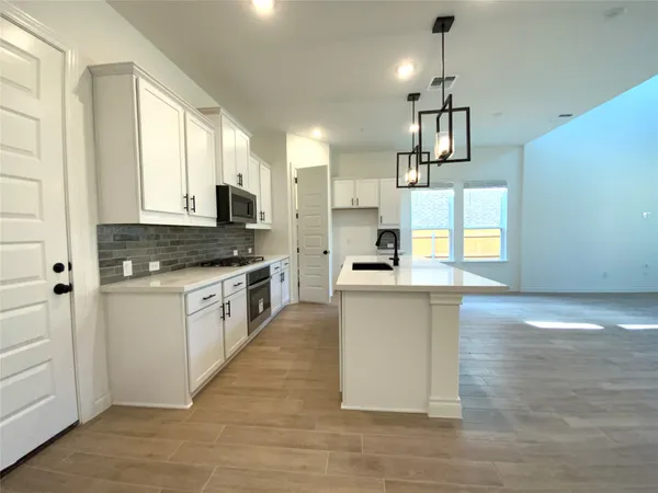 a kitchen with granite countertop a stove a sink and a refrigerator