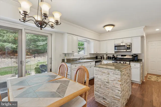 a kitchen with stainless steel appliances granite countertop a stove top oven a sink dishwasher a dining table and chairs with wooden floor