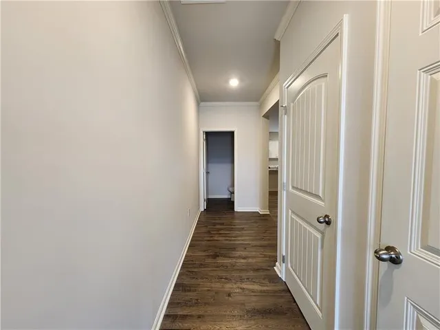 an empty room with wooden floor and kitchen view