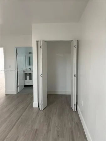an empty room with wooden floor and a kitchen