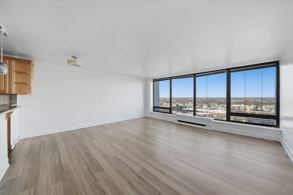 a view of an empty room with a window and wooden floor