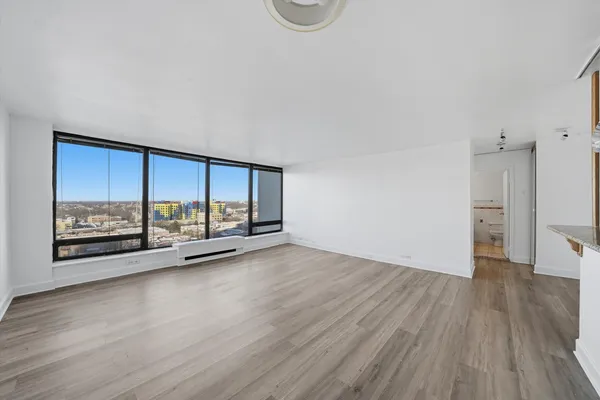 a view of an empty room with a window and wooden floor