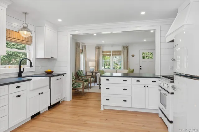 a large white kitchen with granite countertop a large window and white stainless steel appliances