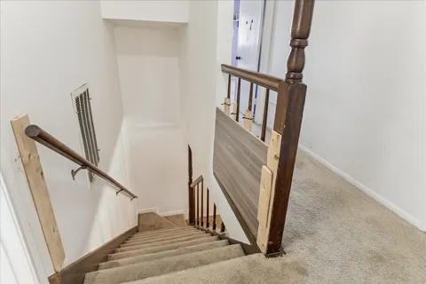a view of staircase with railing and white walls