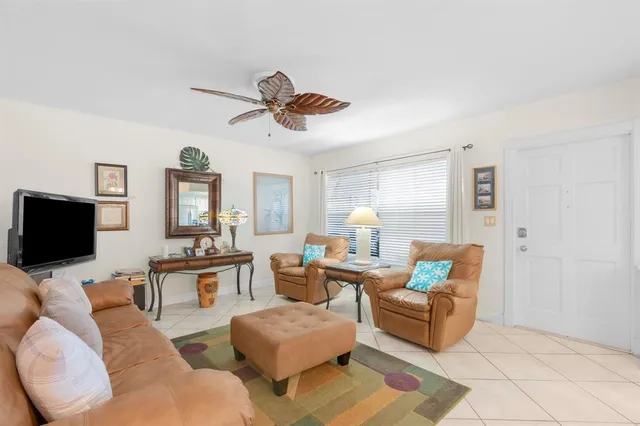 a living room with furniture a ceiling fan and a flat screen tv