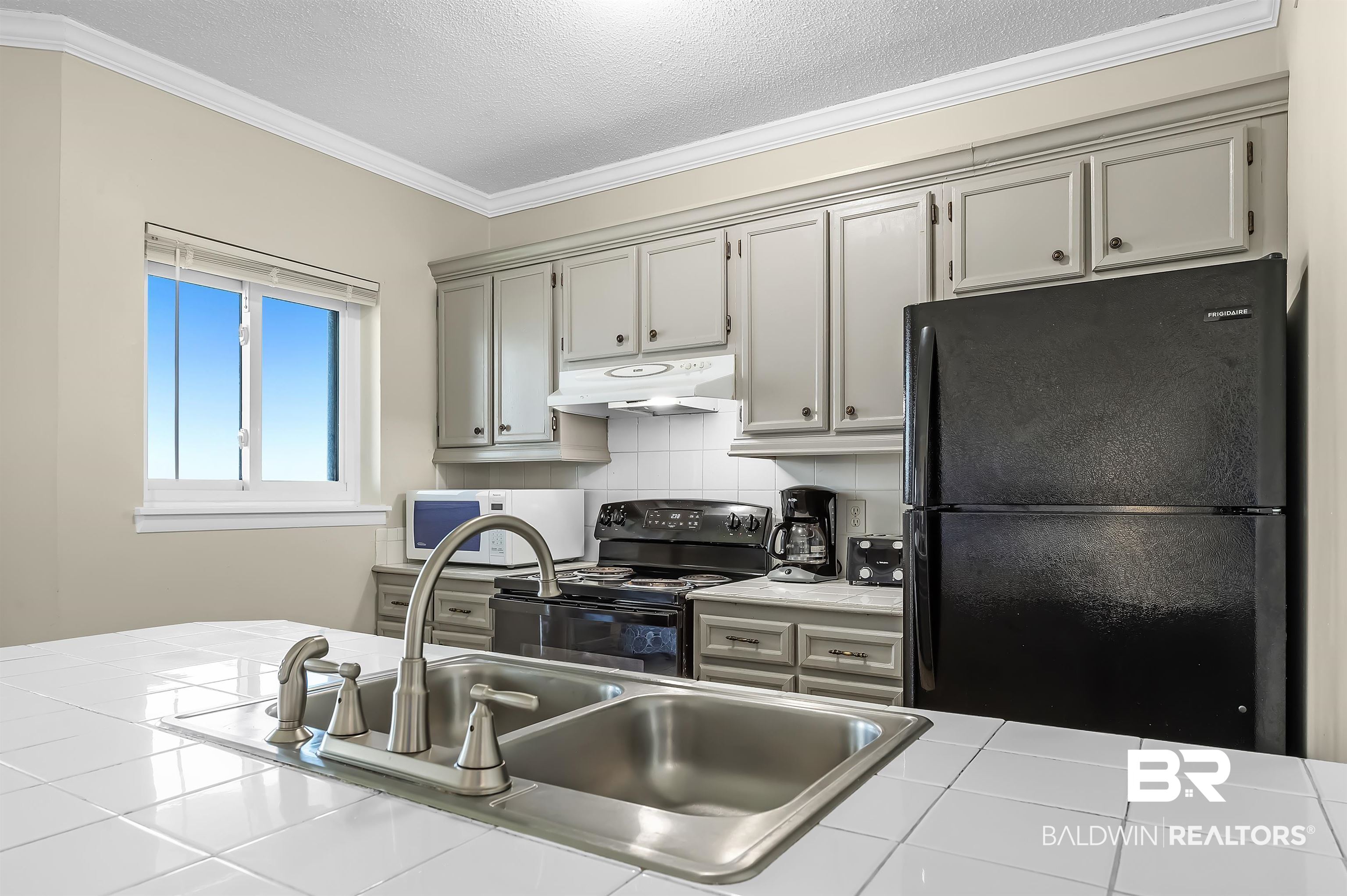 375 Plantation Road, Unit 5409 Gulf Shores, AL 36542 - Photo 10 of 48 Kitchen with tasteful backsplash, black appliances, gray cabinets, crown molding, and tile counters