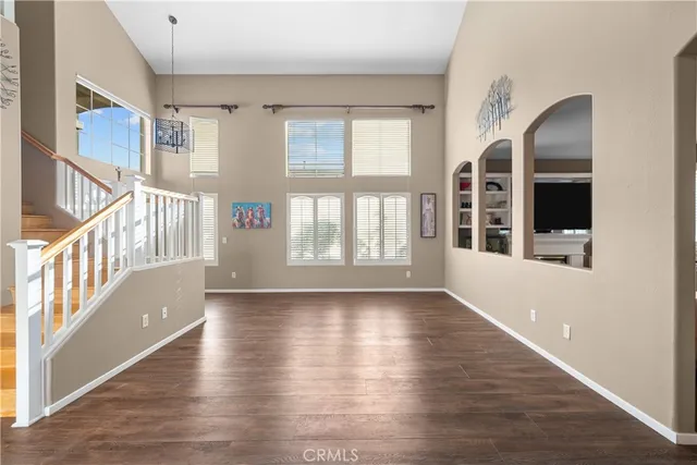 a view of an empty room with wooden floor and windows