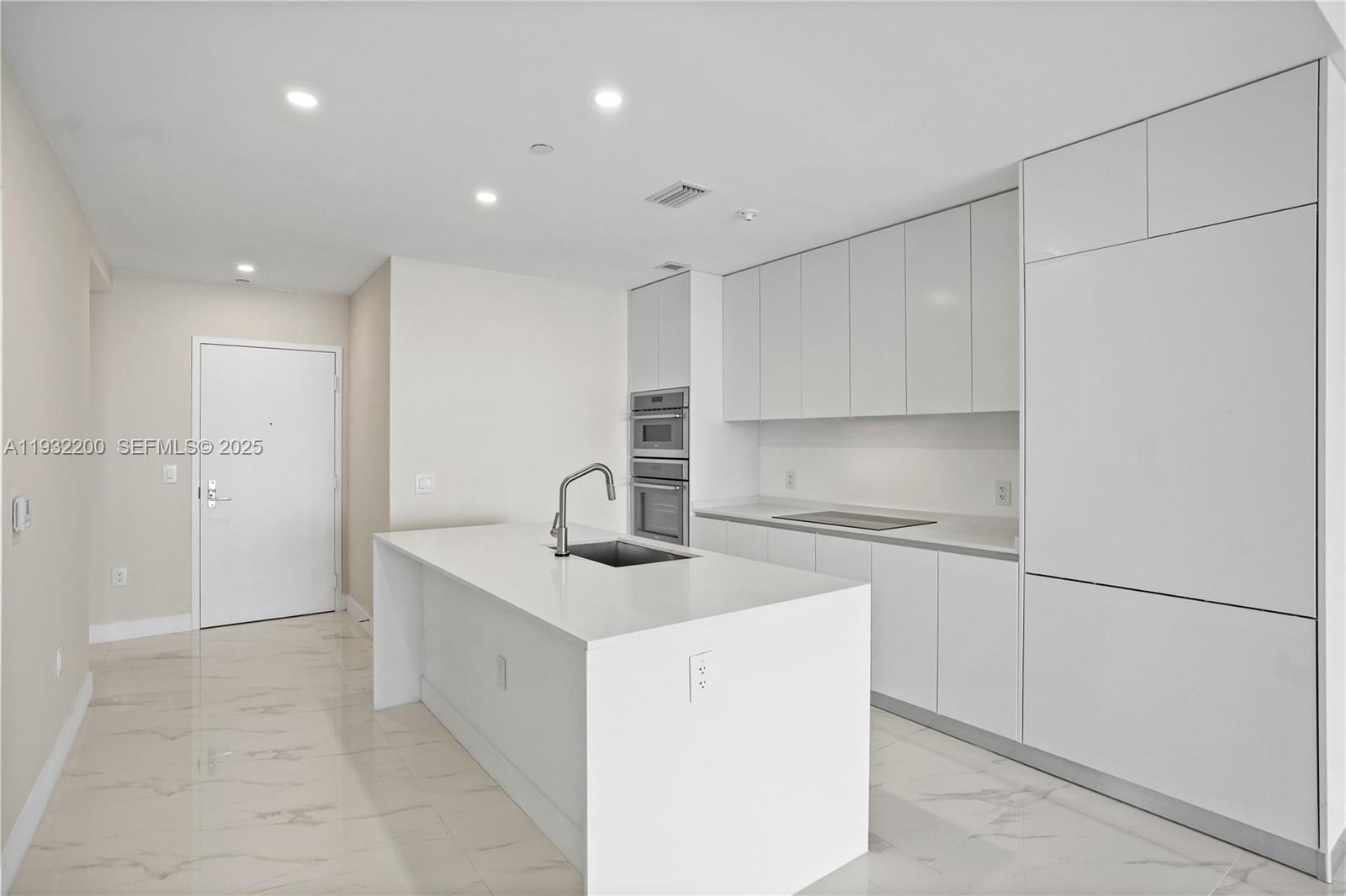 700 Northeast 24th Street, Unit 602 Miami, FL 33137 - Photo 7 of 39 a kitchen with a sink a refrigerator and cabinets