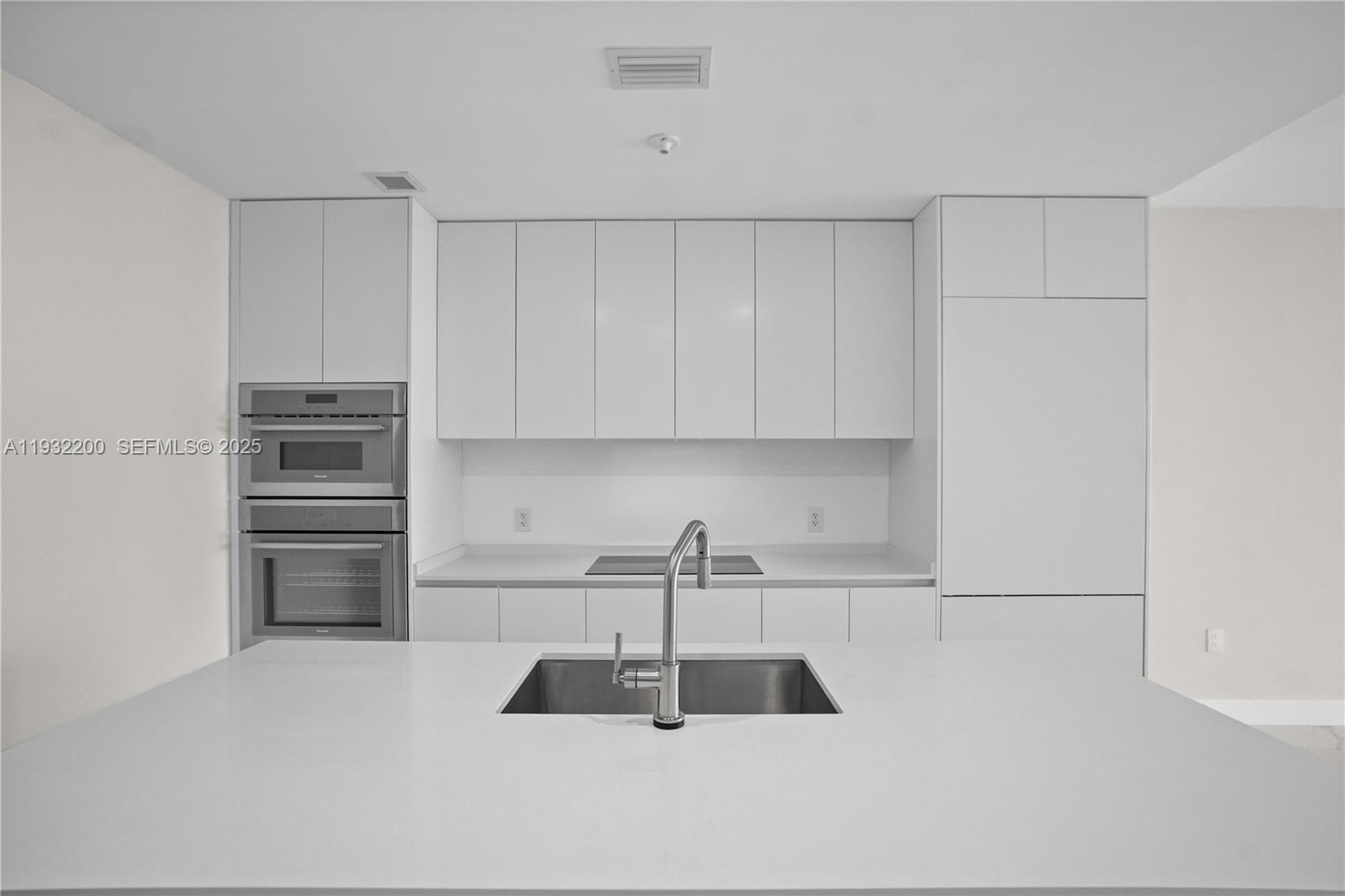 700 Northeast 24th Street, Unit 602 Miami, FL 33137 - Photo 9 of 39 a kitchen with kitchen island a sink stainless steel appliances and cabinets