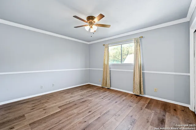 an empty room with wooden floor fan and windows