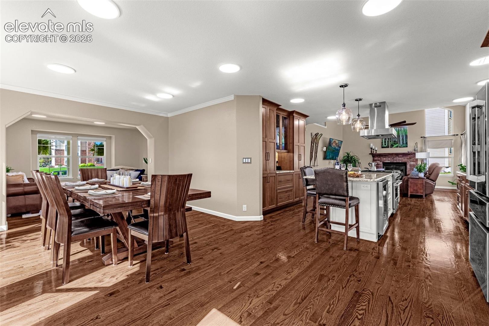 7985 Orchard Path Road Colorado Springs, CO 80919 - Photo 20 of 50 Hardwood flooring throughout, recessed ceiling lights, built-in cabinetry, kitchen island with seating, and a stainless steel range hood