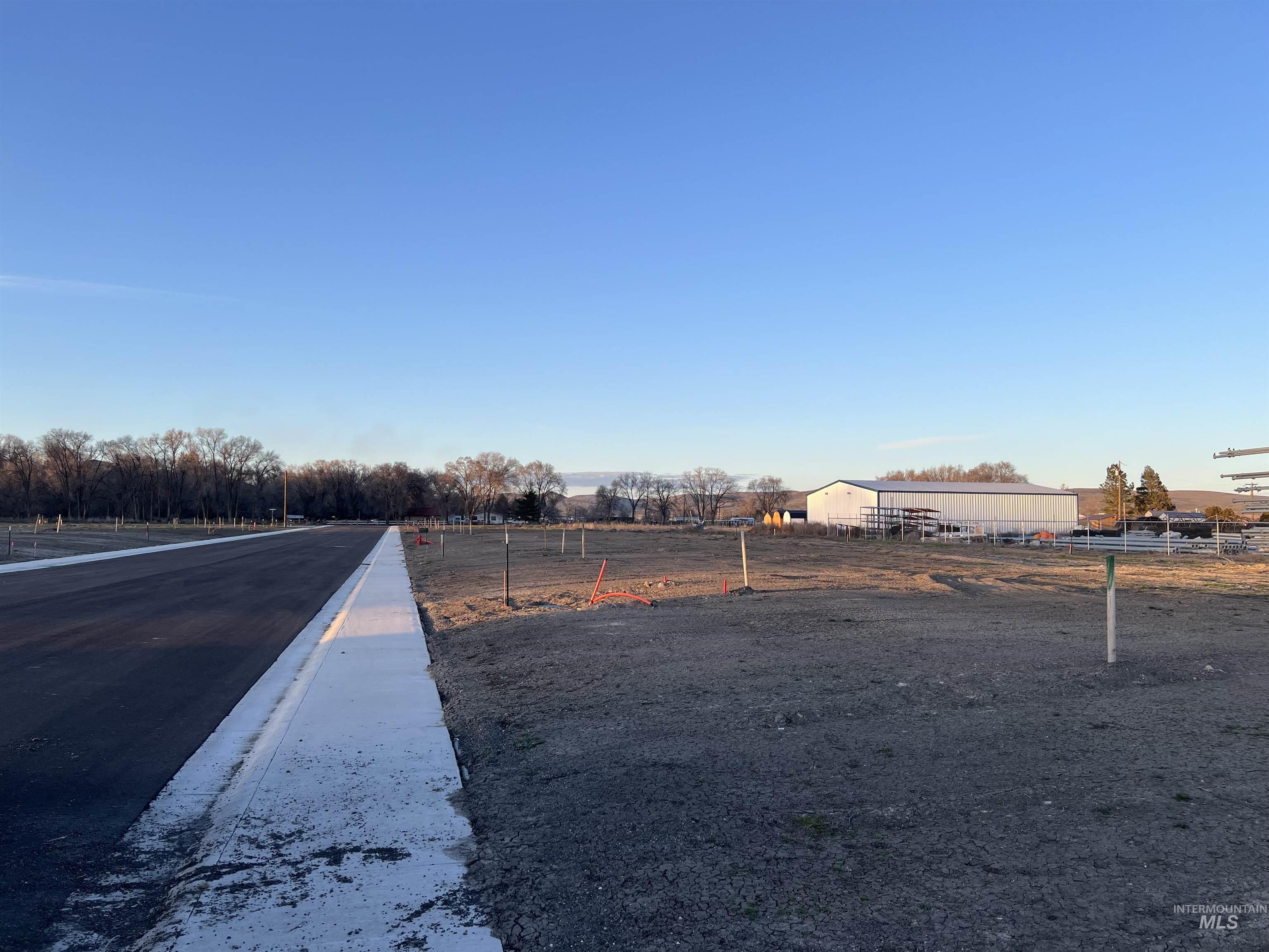View of asphalt street featuring curbs and a rural view