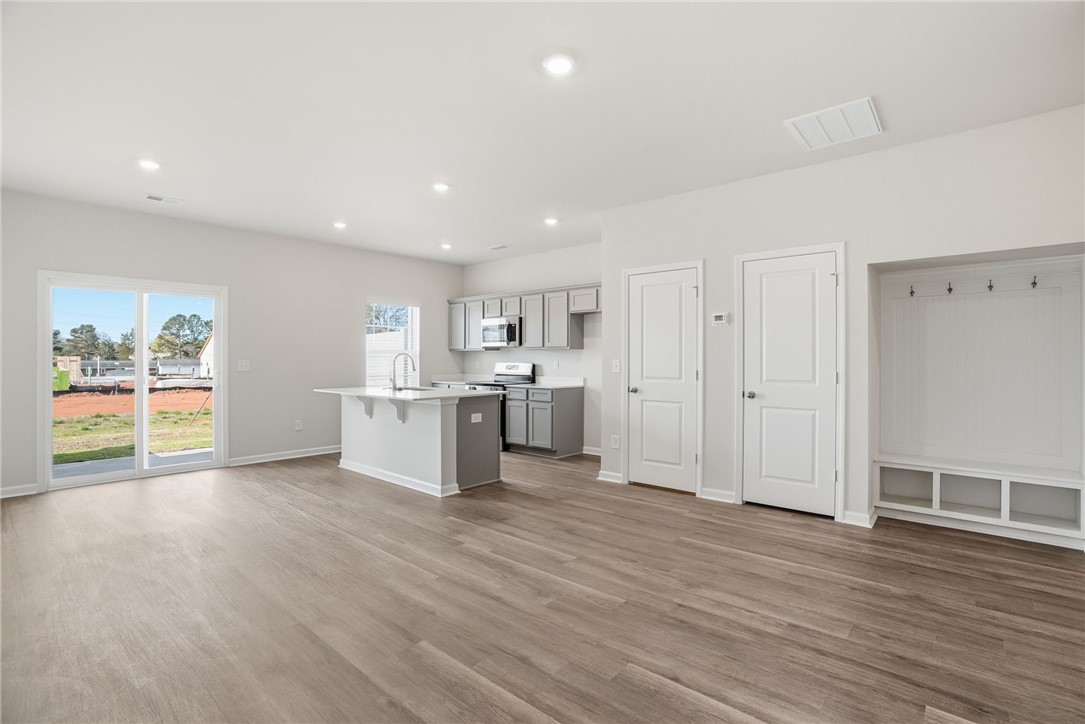 305 Lilac Loop Greenwood, SC 29646 - Photo 8 of 25 An inviting open-concept layout connects the well-appointed kitchen with sun-filled living spaces, featuring resilient wood flooring.