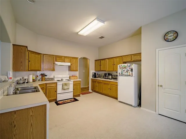 a kitchen with cabinets a sink and white appliances