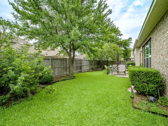 a view of a backyard with table and chairs and potted plants and large trees