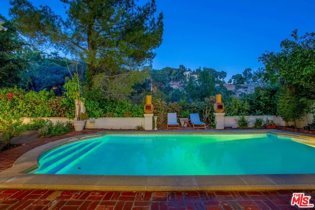 a view of a swimming pool with lawn chairs under an umbrella
