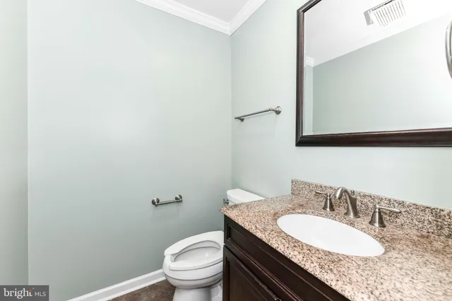 a bathroom with a granite countertop sink a mirror and a toilet