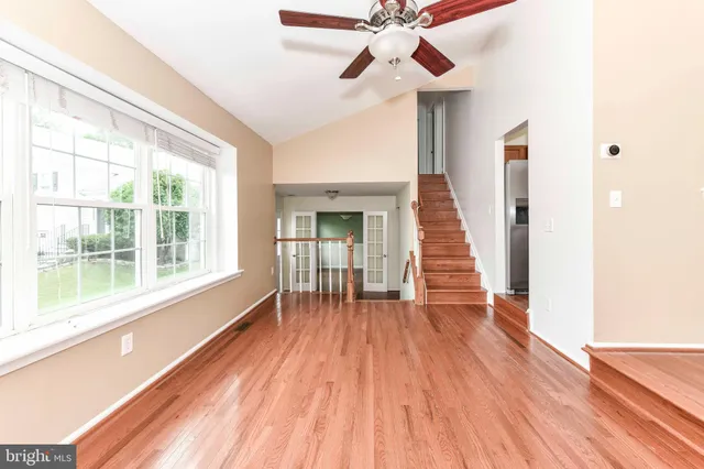 a view of empty room with wooden floor and fan