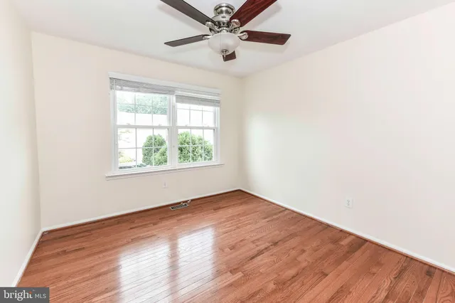 an empty room with wooden floor closet and windows