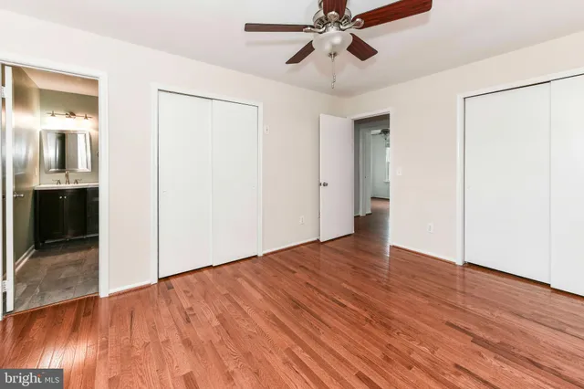 an empty room with wooden floor fan and windows