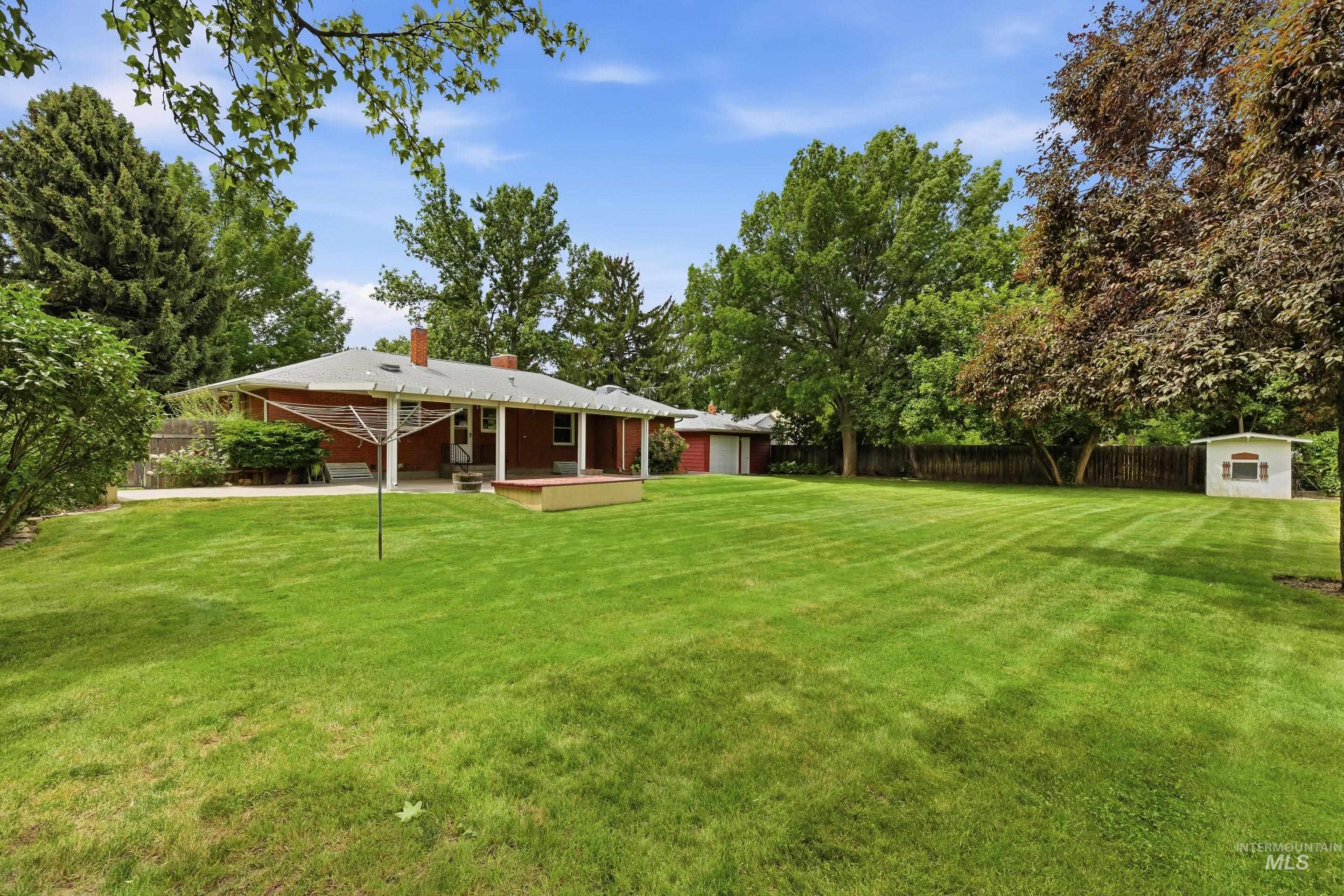 504 West Howe Street Boise, ID 83706 - Photo 47 of 47 Expansive green lawn with mature trees, a red brick exterior, and a covered back porch with white columns