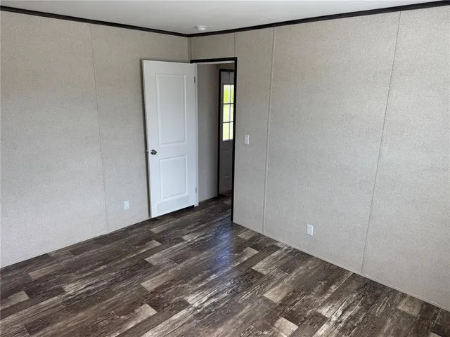 a view of an empty room with wooden floor and closet