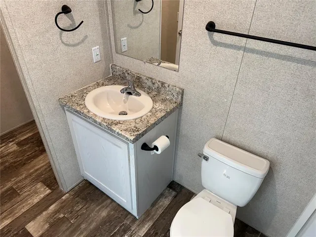 a bathroom with a granite countertop sink toilet and a mirror