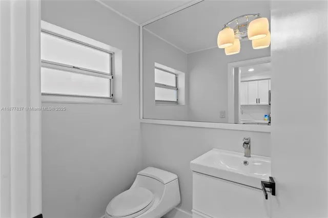 a bathroom with a toilet sink vanity and mirror