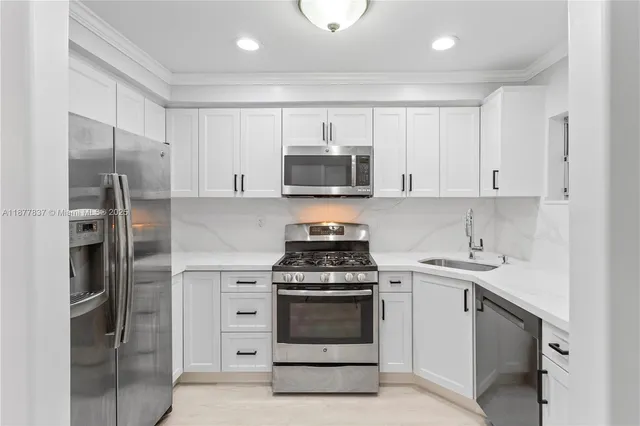 a kitchen with stainless steel appliances white cabinets and a stove top oven