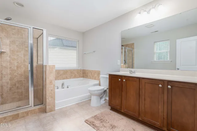 a spacious bathroom with a bathtub shower sink mirror and toilet