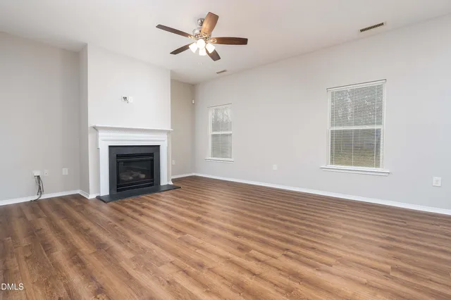 a view of empty room with fireplace and wooden floor