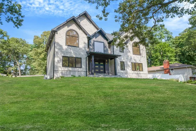 a view of a brick house with a big yard and large trees