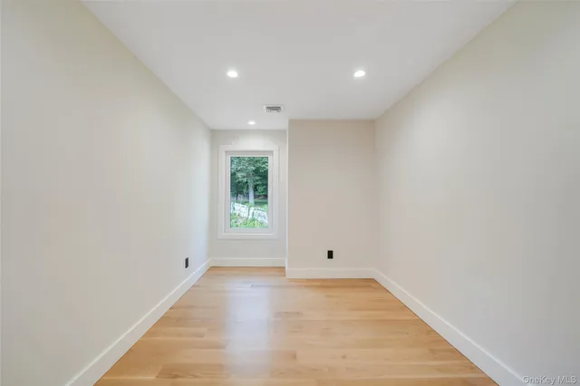 an empty room with wooden floor and window
