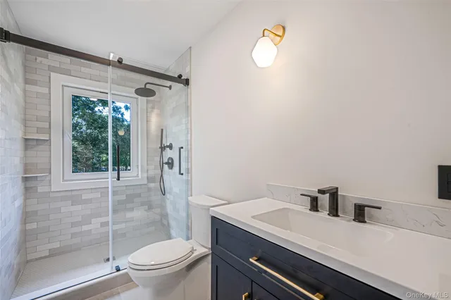 a bathroom with a granite countertop sink mirror vanity and toilet