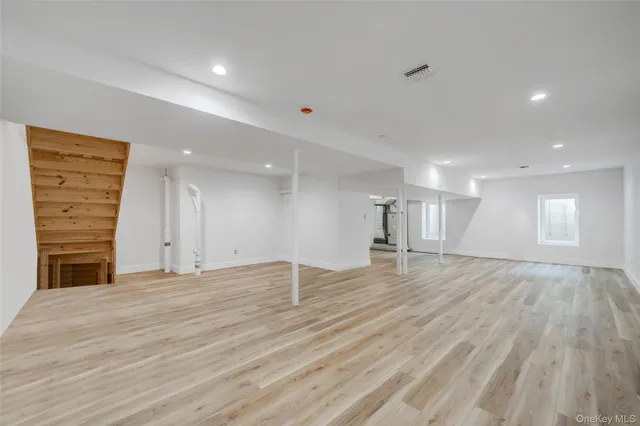 a view of empty room with wooden floor and kitchen