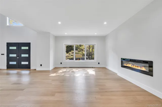 a view of an empty room with wooden floor and window