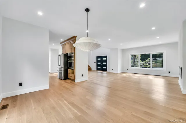 a view of an empty room with a window and kitchen view