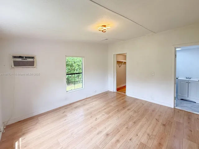 a view of empty room with window and wooden floor