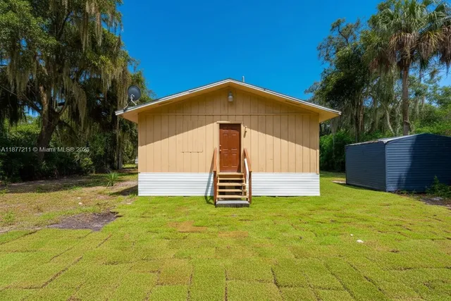 a front view of house with yard and trees in the background