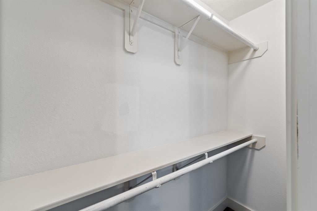 1305 Idylwild Street Houston, TX 77009 - Photo 16 of 31 This is a spacious walk-in closet with two shelves and hanging rods, offering ample storage space for clothing and accessories. The walls are painted white, providing a clean and bright appearance.