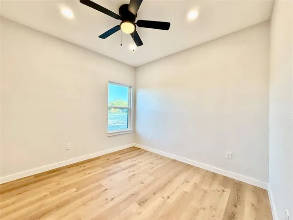 an empty room with a window and a ceiling fan