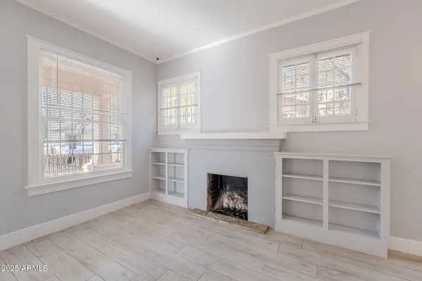 an empty room with windows and fireplace
