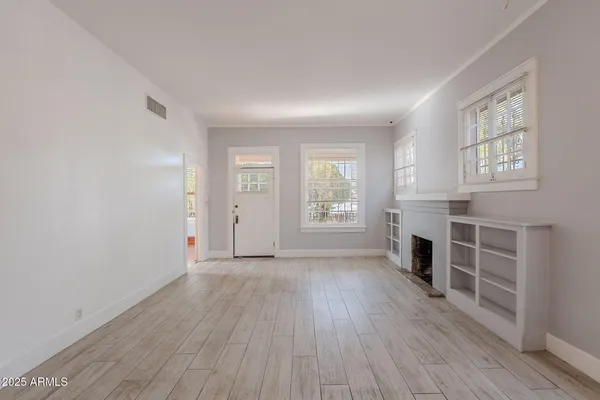 an empty room with windows hardwood floor and fireplace