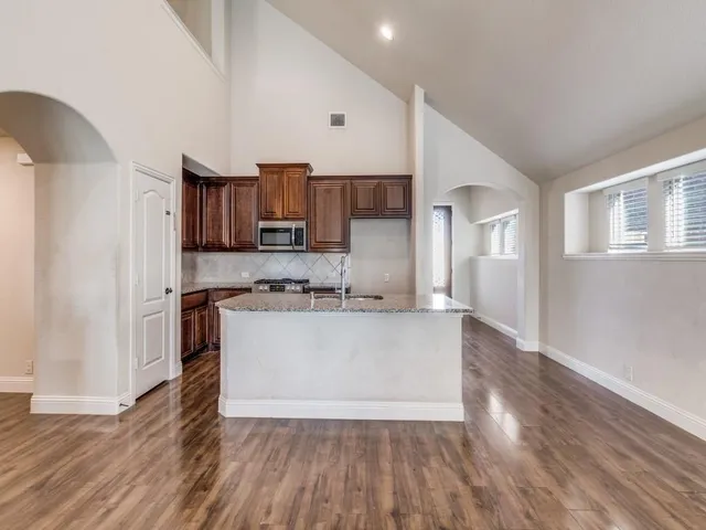 a large kitchen with cabinets wooden floor and stainless steel appliances